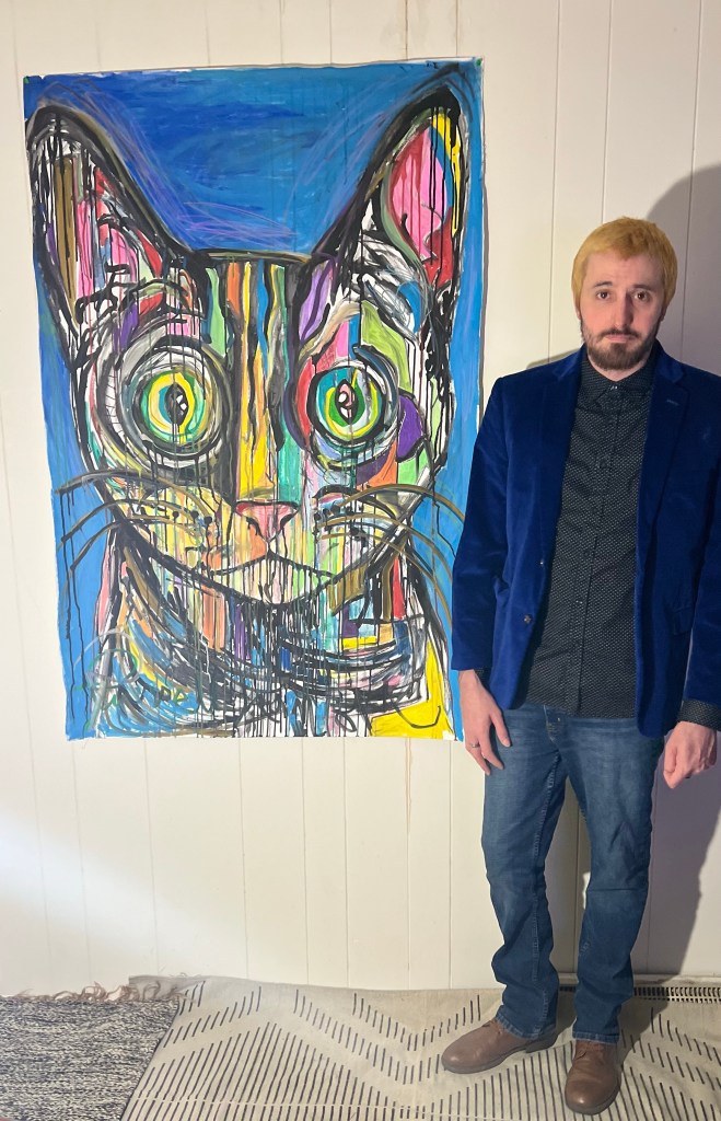 Artist Russell Frantom standing with one of his cat paintings. November 2023 