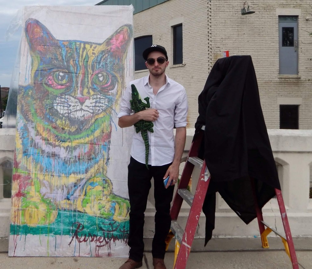 Artist Russell Frantom shows a large cat painting at artbeat in downtown south bend Indiana 