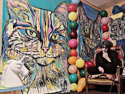 Artist Russell frantom poses with giant colorful cat paintings 