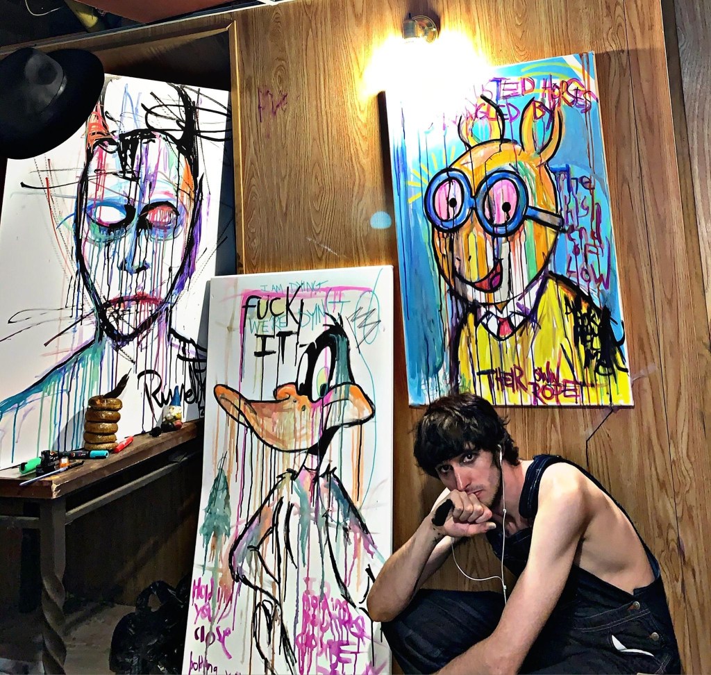 Artist Russell frantom in art studio with cartoon series paintings and artwork 2020 
