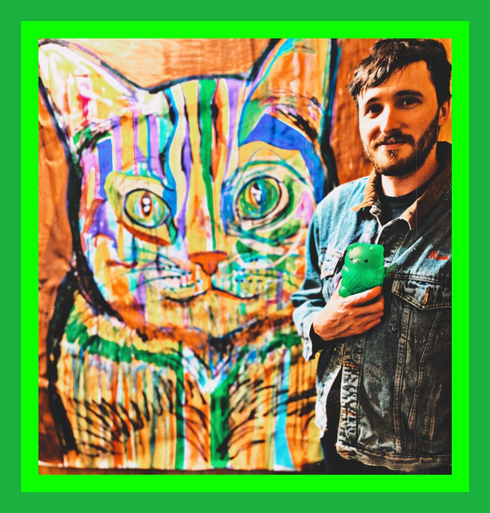 Artist Russell Frantom stands with one of his colorful cat paintings in 2021 