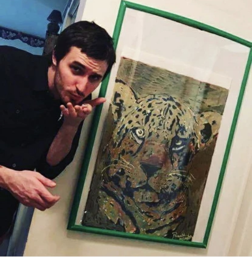 Russell frantom the artist stands with a painting he made of a leopard. Mixed media on paper. 